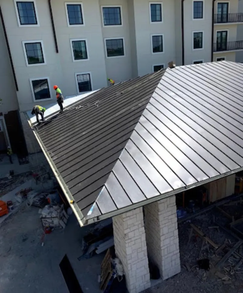 Crew installing standing seam metal roof panels on a commercial project in Conway